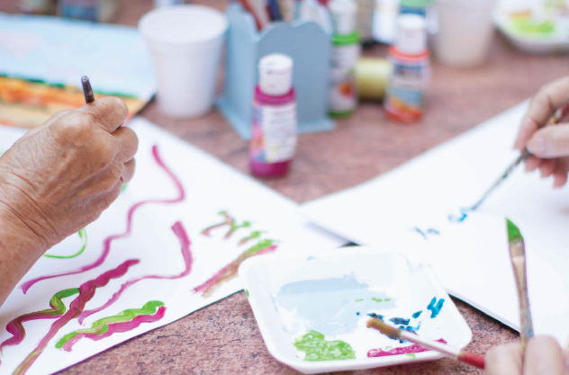 2 personas mayores pintando con pinceles y temperas en un patio de Cohabitam 